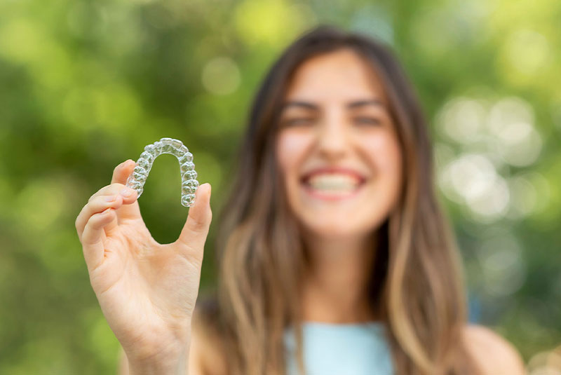 patient smiling with invisalign in hand