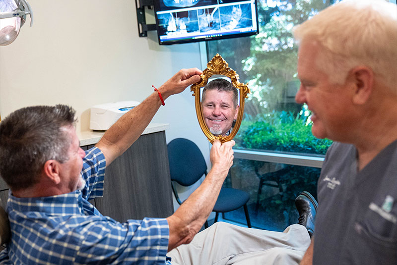 Patient looking into Mirror After dental Implants